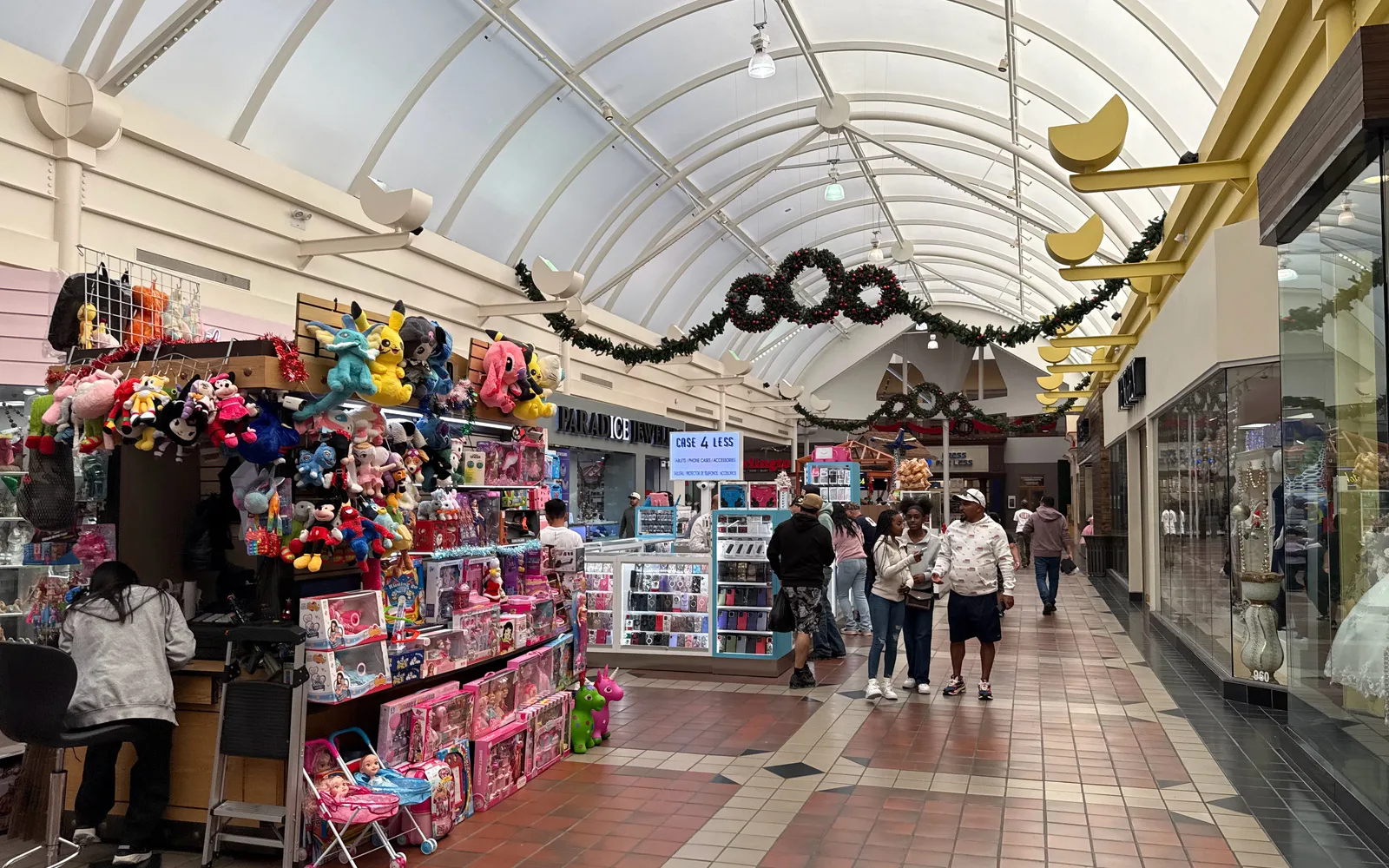 Interior view of a shopping mall showing retail storefronts, modern lighting, and the built environment of a commercial center